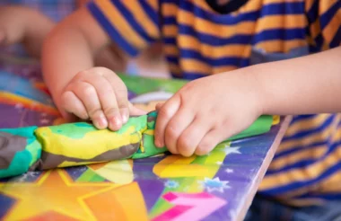 A child molding and shaping colorful clay with their hands.