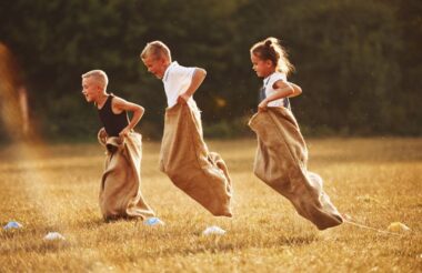 Jumping sack race outdoors in the field. Kids having field game fun at sunny daytime