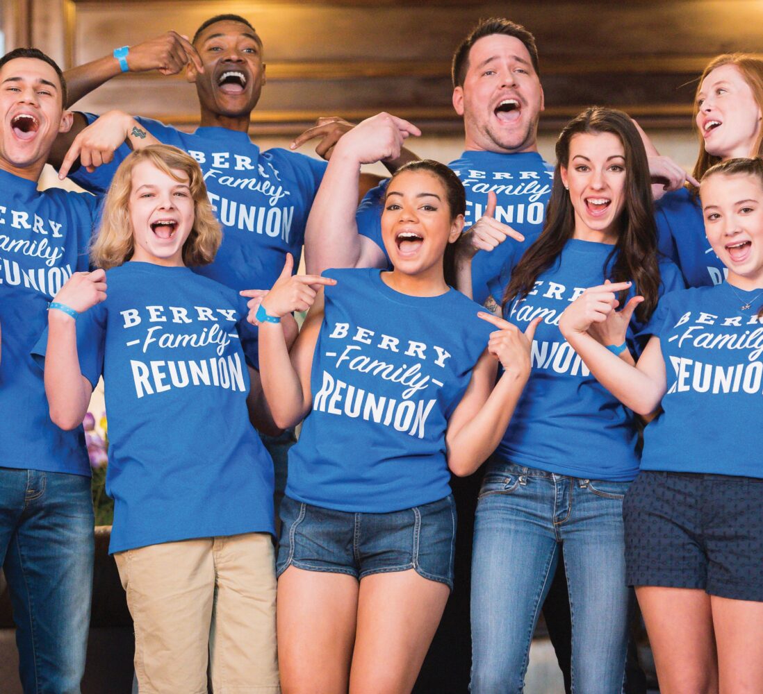 A group of people wearing matching Berry Family Reunion shirts smile and pose together indoors.