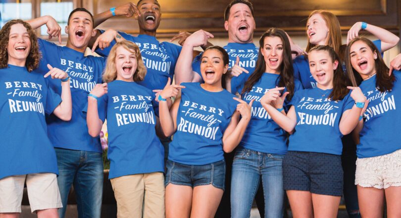 A group of people wearing matching Berry Family Reunion shirts smile and pose together indoors.